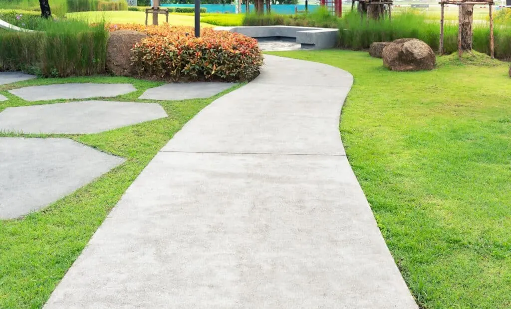 Curved concrete walkway with stepping stones and landscaping